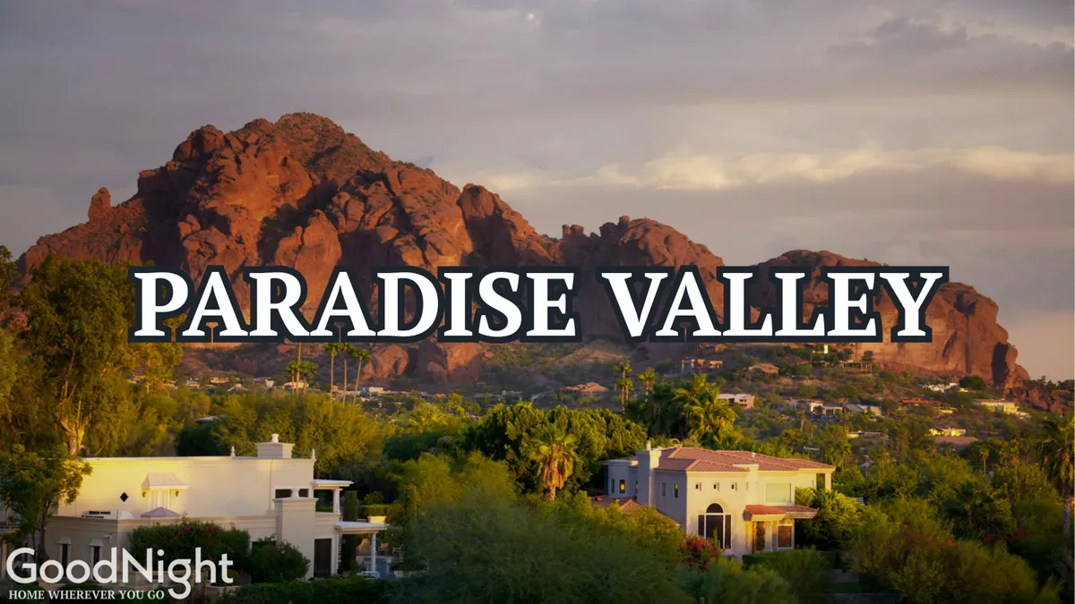 A stunning view of the mountains with residential homes nestled among lush greenery. The lighting suggests either a sunrise or sunset, with warm, golden tones enhancing the tranquil environment. The scene evokes a sense of connection to nature and highlights the breathtaking natural surroundings of Scottsdale.