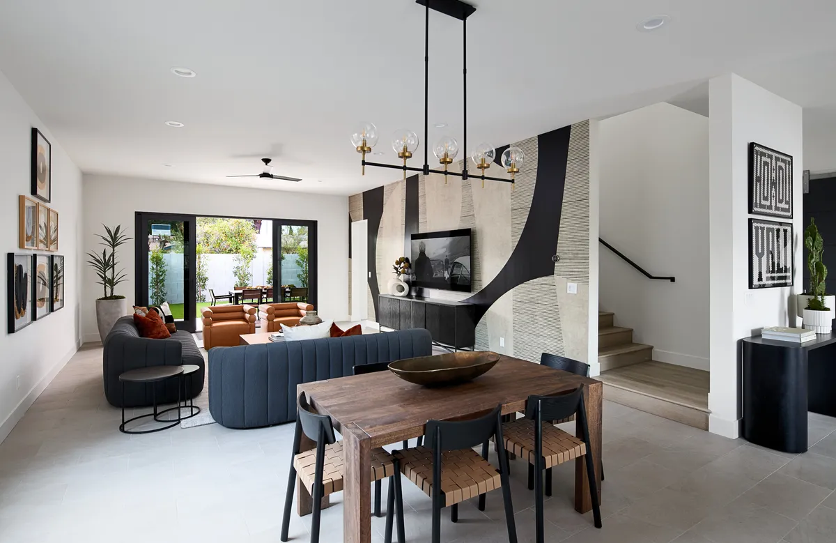 This image presents an elegant dining area complete with a sophisticated dining table, plush sofa set, contemporary wall art, and a statement chandelier. The décor is modern and cozy, reinforcing the atmosphere described in the section.